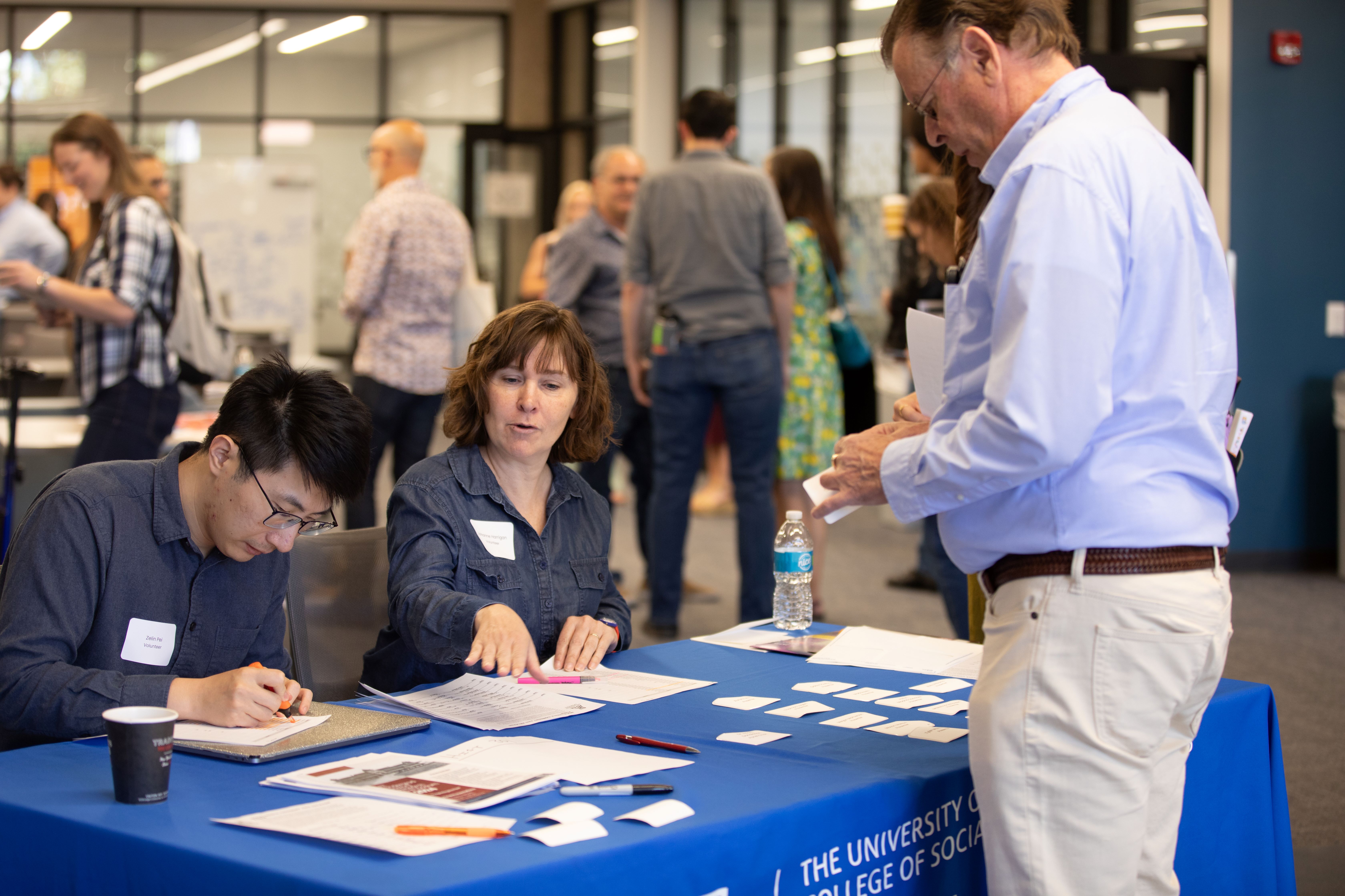 two graduate students working at the check in table