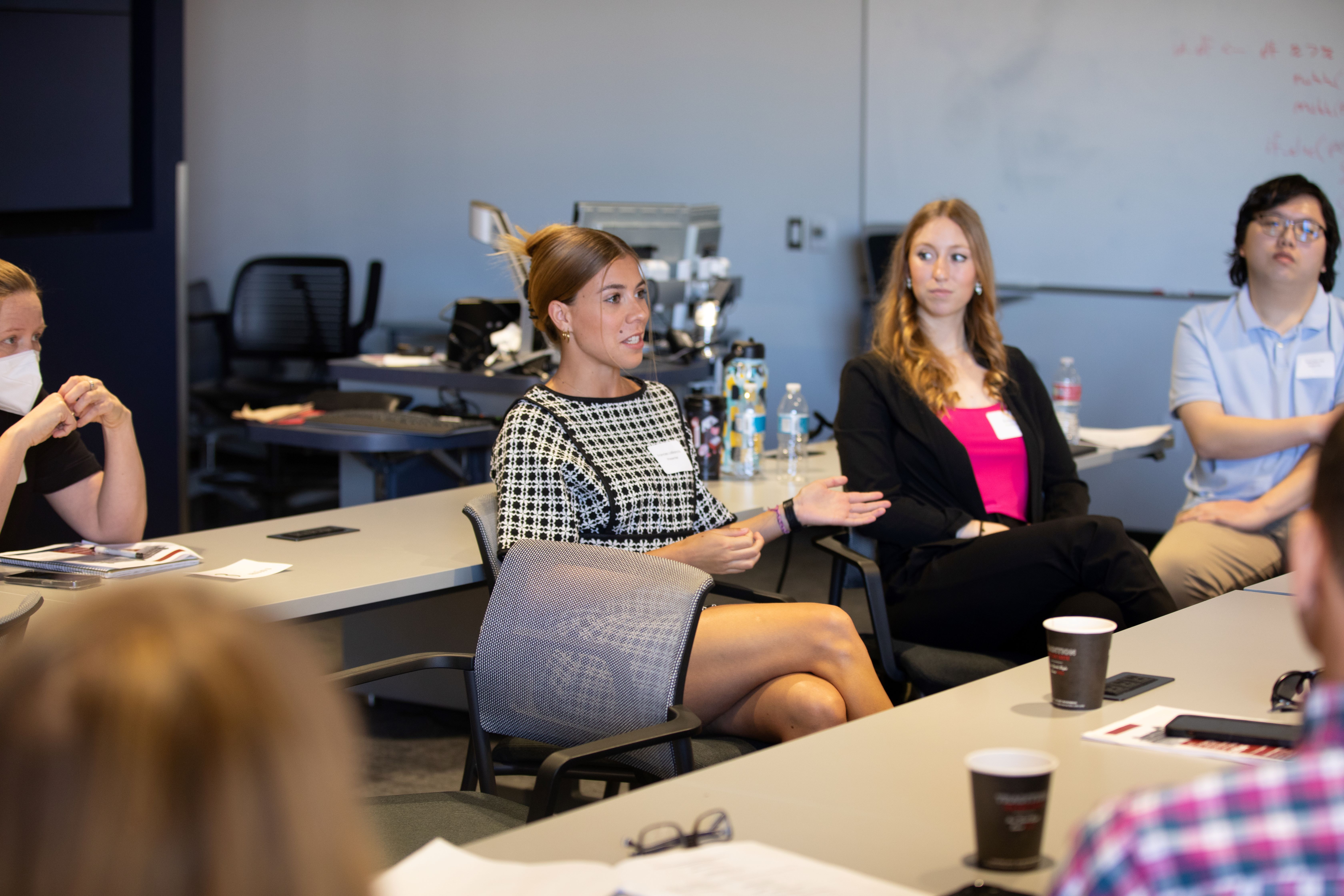 undergraduate student speaks to audience as the rest listen