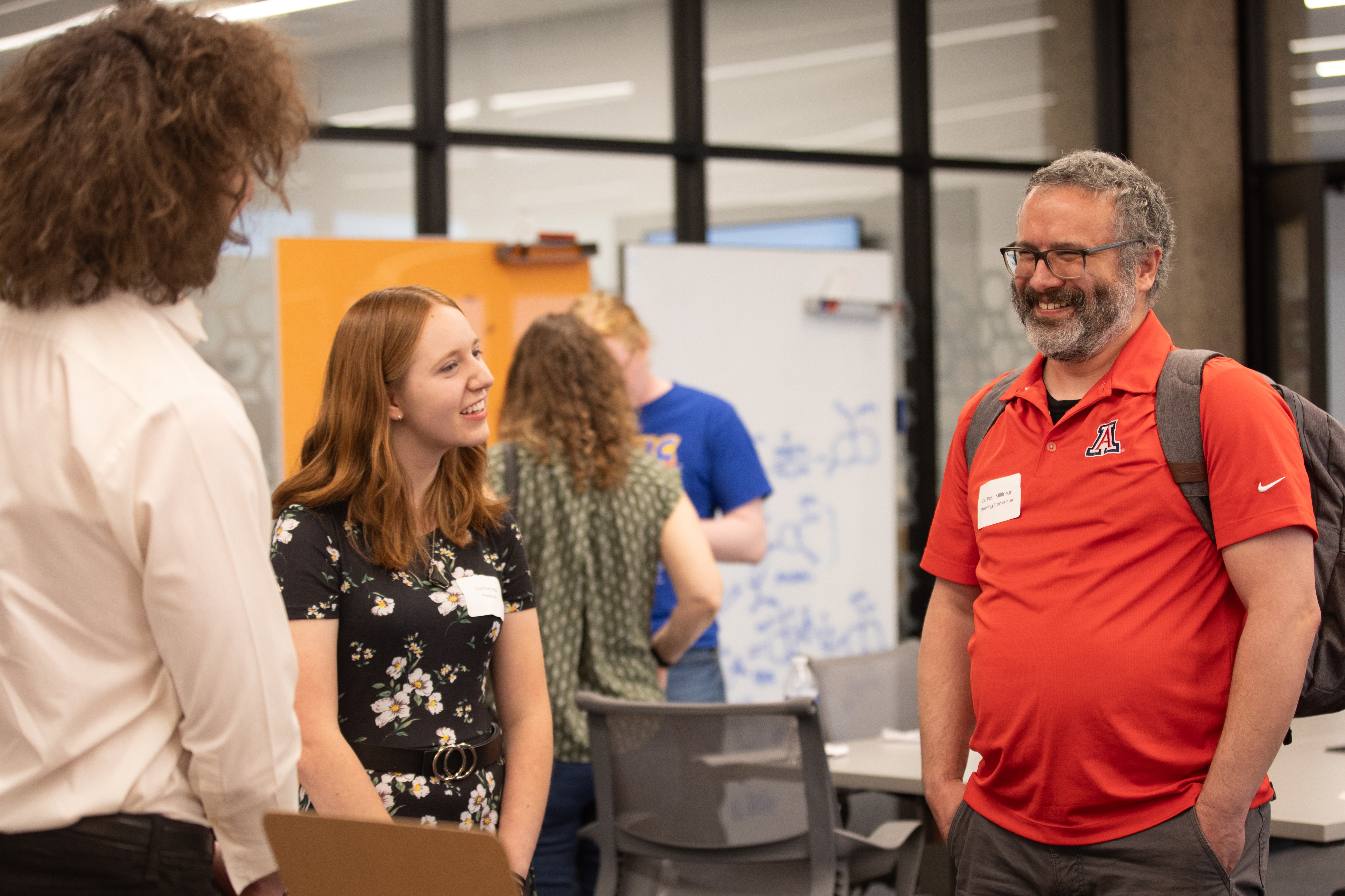 two undergraduate students and faculty member smile while talking