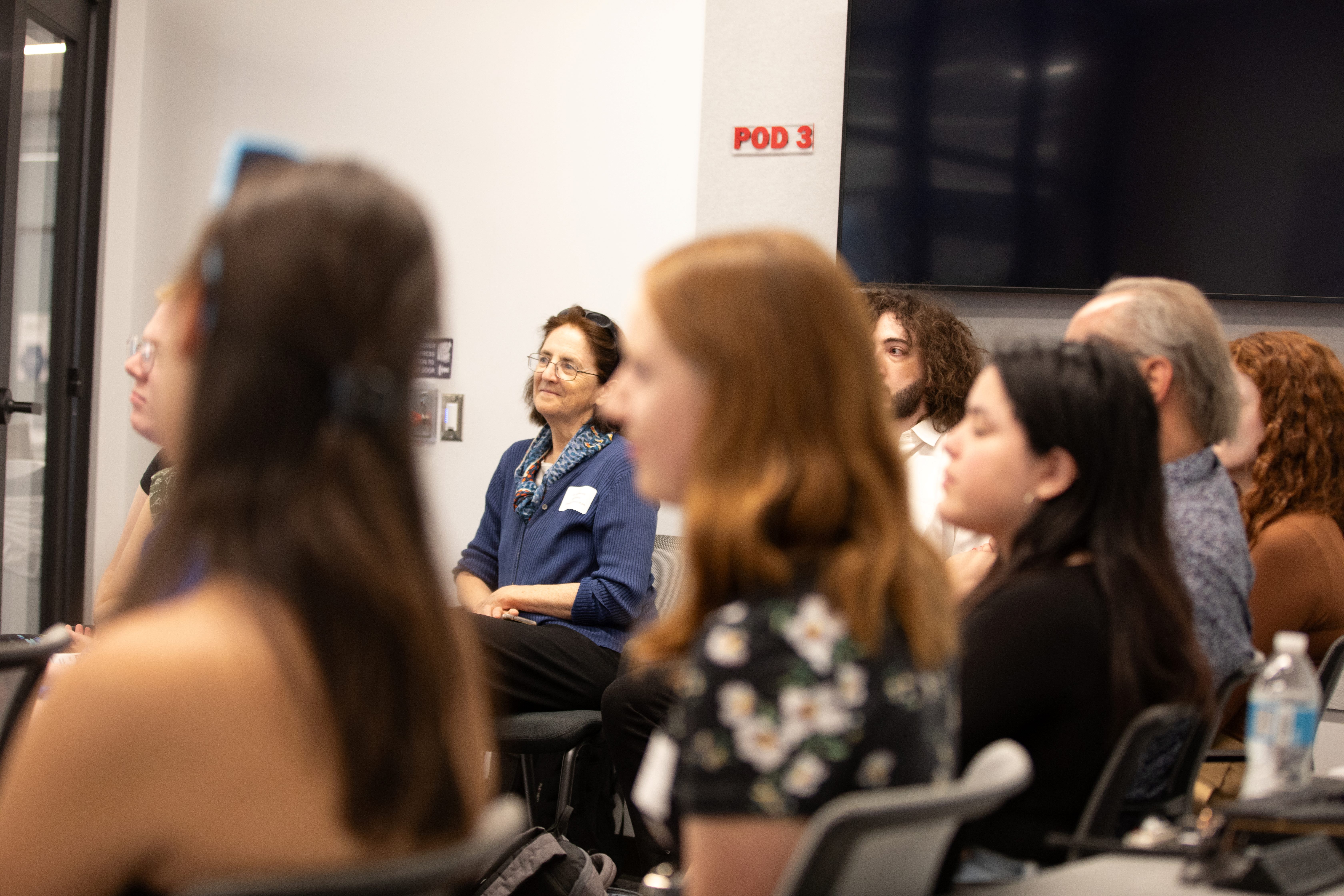 professor surrounded by people smiles from presentation audience