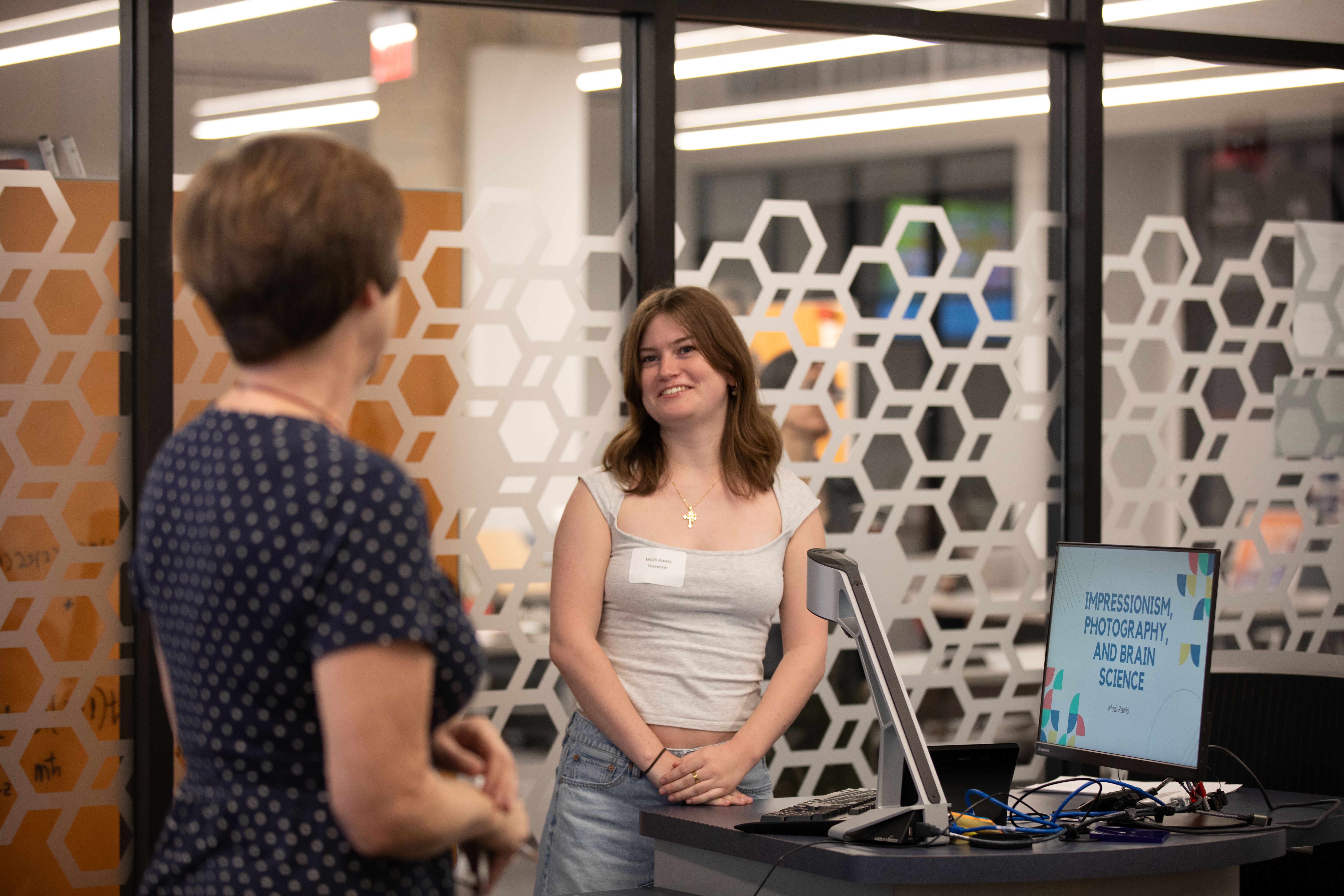 undergraduate student smiles and listens to faculty member